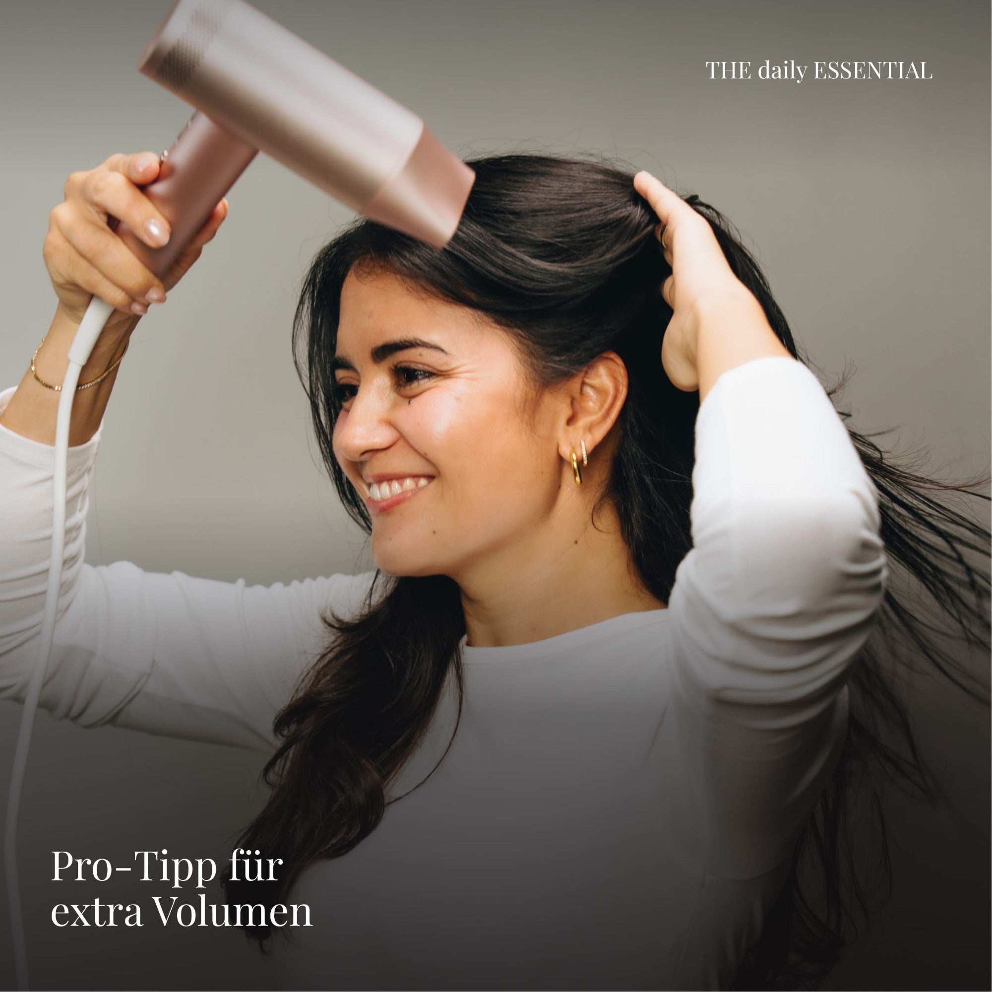 Frau föhnt ihren Ansatz an, Pro-Tipp für extra Volumen mit THE daily ESSENTIAL